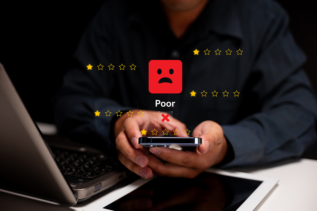 Person holds a smartphone with a poor rating and sad face emoji