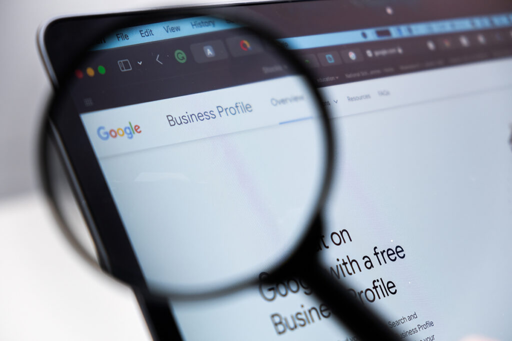 Google Business Profile logo on the screen of laptop through magnifying glass
