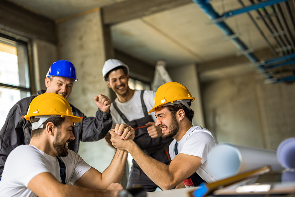 Two construction workers arm wrestling during a lunch break with